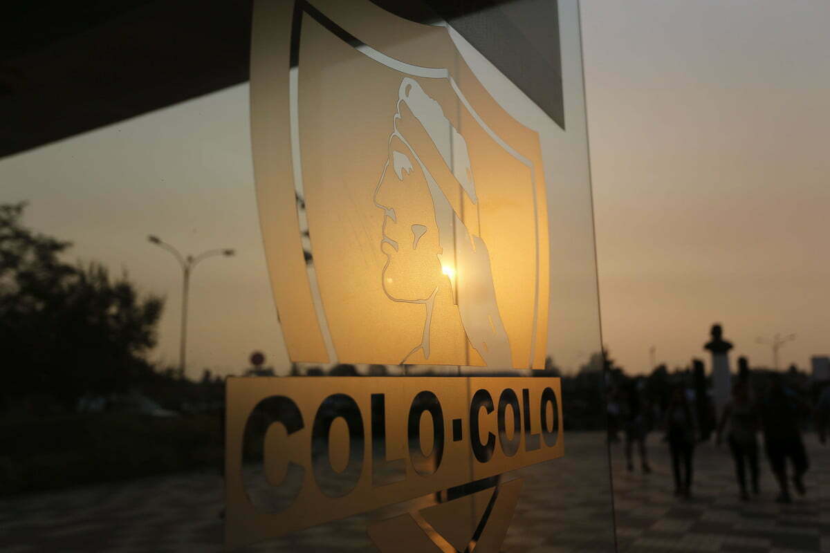 Fotografía a la puerta de entrada del sector Océano en el Estadio Monumental, instante donde se puede observar el escudo de Colo-Colo en contraste al sol durante un día de atardecer.