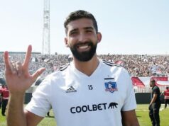 Emiliano Amor con la mano derecha levantada en la cancha del Monumental