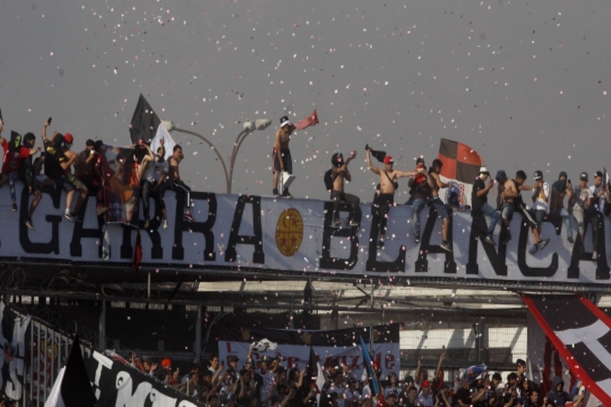 Hinchas sobre la cornisa del Estadio Monumental junto a un lienzo de la Garra Blanca.