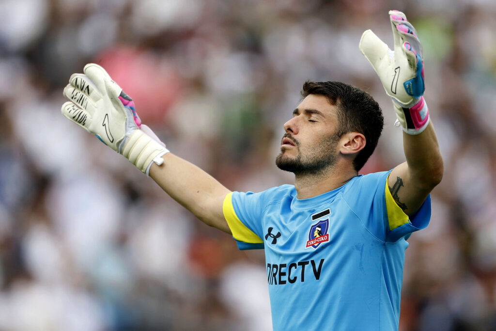 Paulo Garcés con las manos arriba y rezando en medio de un partido con la camiseta de Colo-Colo.