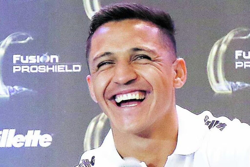 Primer plano a Alexis Sánchez sonriendo mientras entrega una conferencia de prensa con la camiseta del Olympique de Marsella.