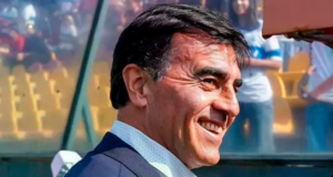 Primer plano al rostro de Gustavo Quinteros sonriendo mientras se dirige a la banca del Estadio Santa Laura.