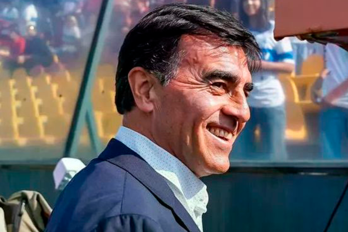 Primer plano al rostro de Gustavo Quinteros sonriendo mientras se dirige a la banca del Estadio Santa Laura.