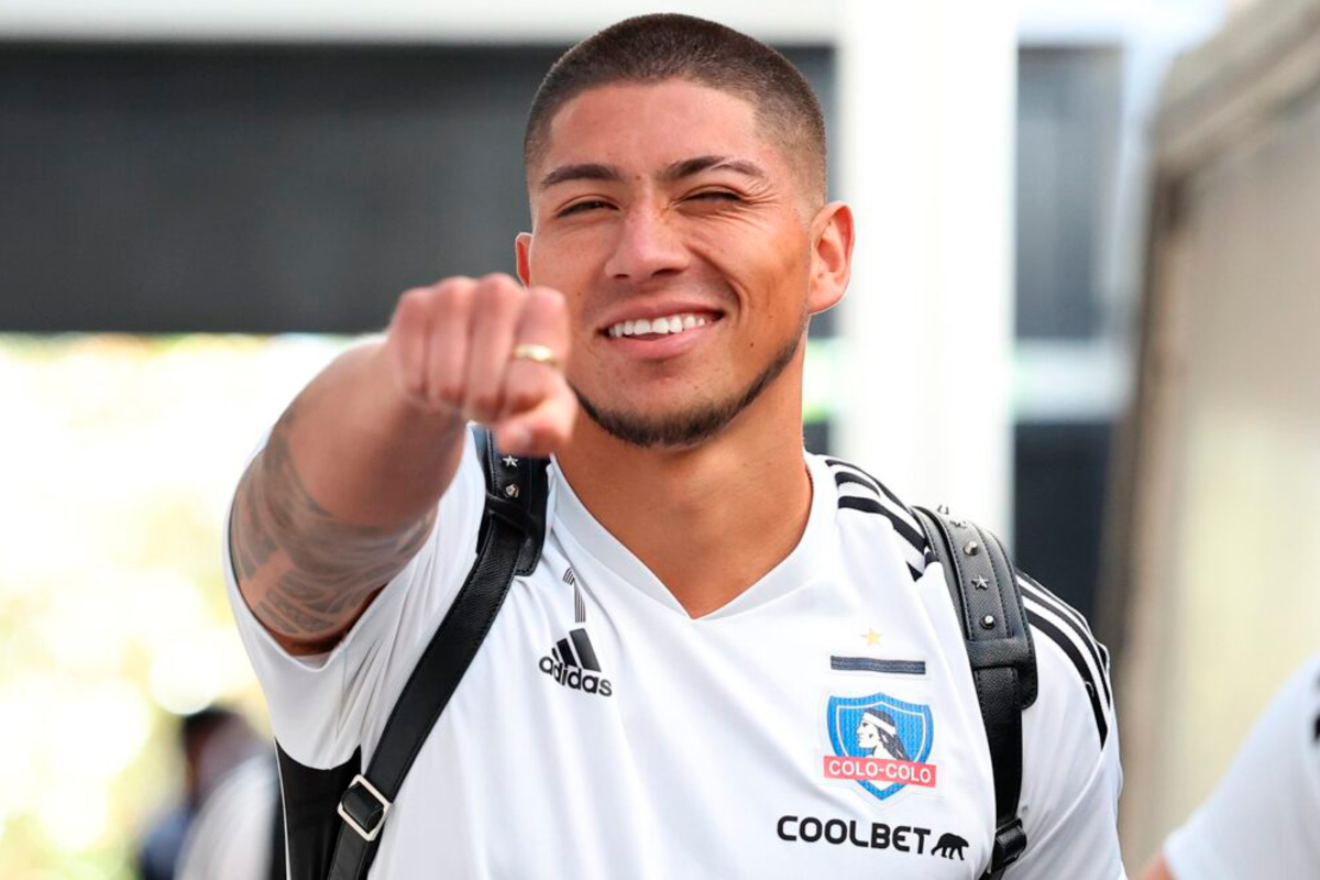 Brayan Cortés con el puño el alto y con una gran sonrisa entrando al sector de camarines del Estadio Monumental.