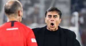 Gustavo Quinteros con cara de sorpresa y la boca abierta mirando al árbitro