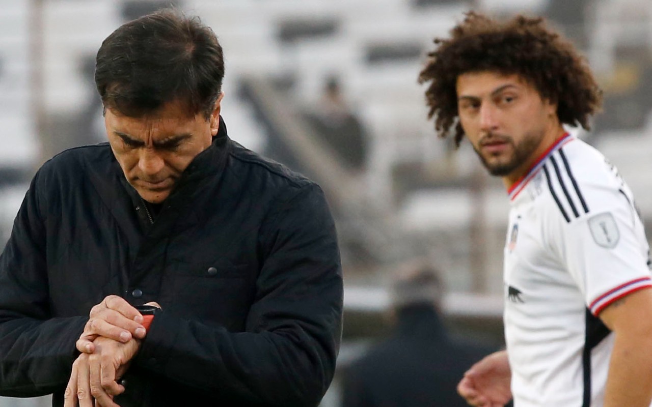 Gustavo Quinteros mirando su reloj y Maximiliano Falcón mirándolo en el fondo