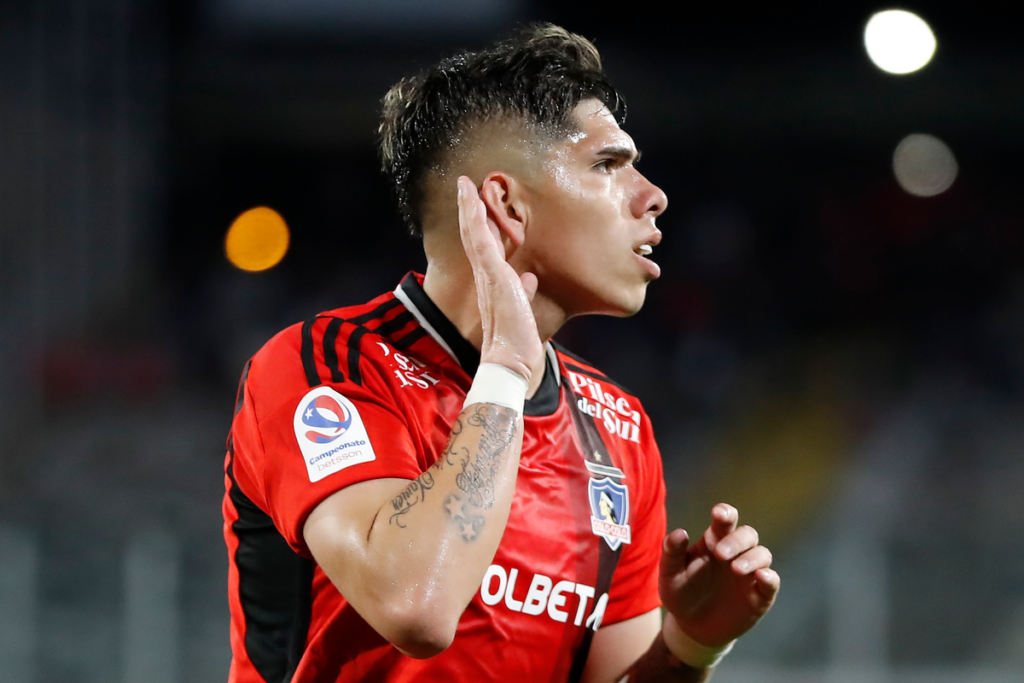 Carlos Palacios celebrando con las manos en la oreja un gol con la camiseta de Colo-Colo.