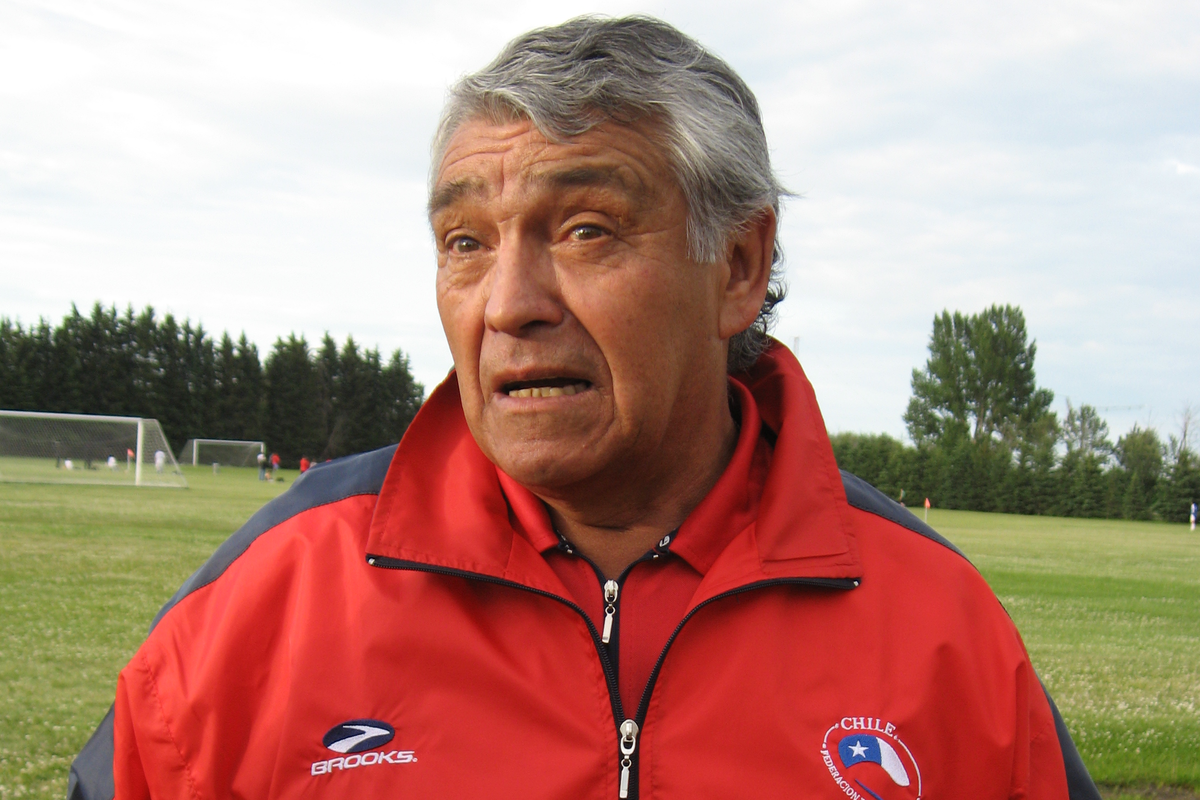 José Sulantay con el buzo de entrenador de la selección chilena en medio de una entrevista o conversación.