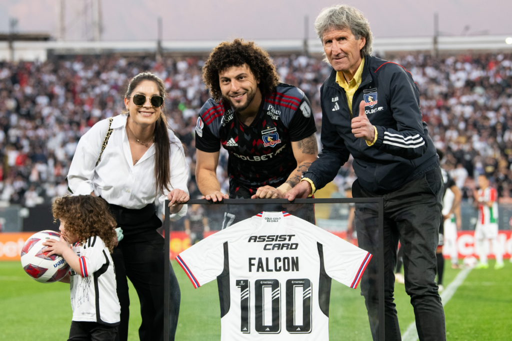 Daniel Morón, Florencia Pouso y Domingo Falcón posan junto una camiseta en homenaje a Maximiliano Falcón, quien sobrepasó los 100 partidos oficiales en Colo-Colo.