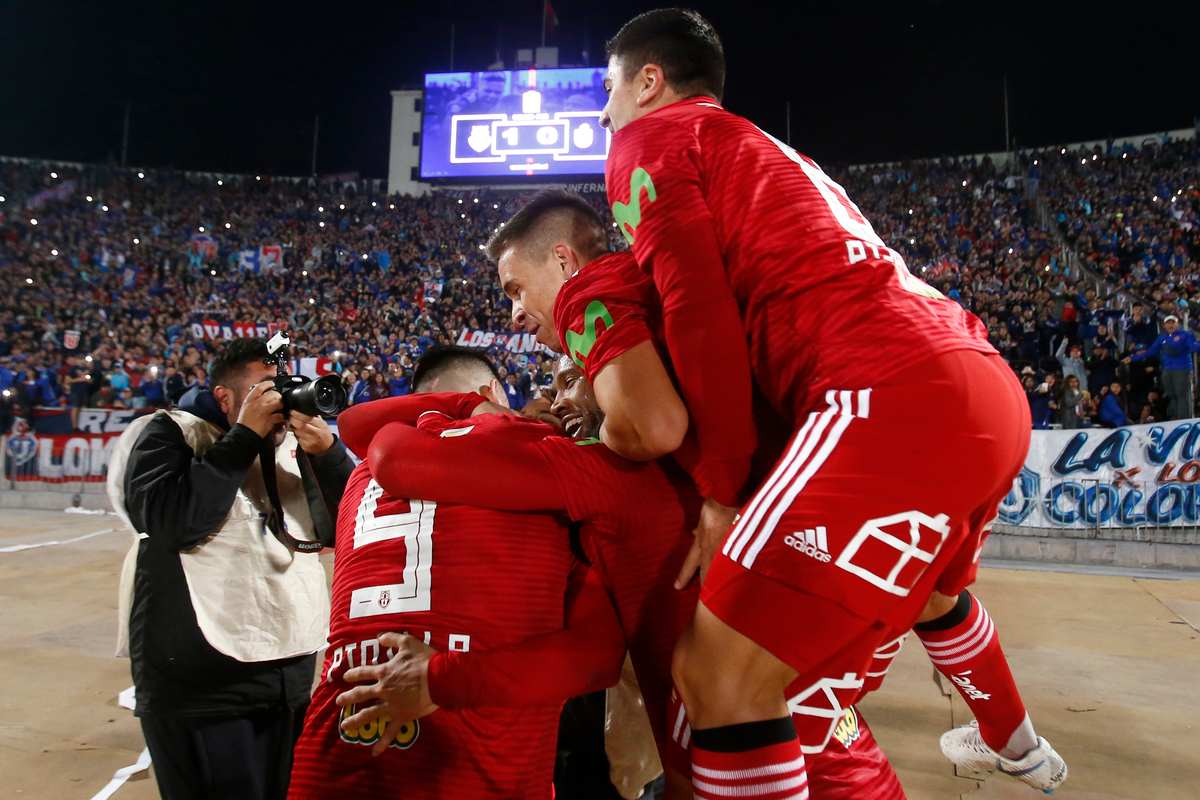 Futbolistas de Universidad de Chile se abrazan tras anotar un gol en un repleto Estadio Nacional.