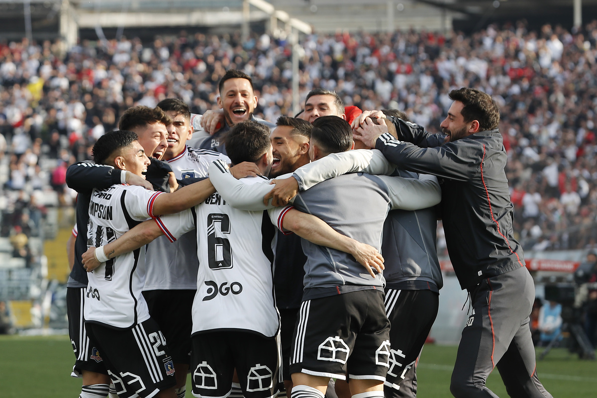 Jugadores de Colo-Colo abrazados celebrando un gol.