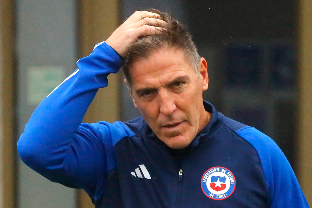 Eduardo Berizzo se toma la cabeza mientras viste el buzo de la selección chilena.