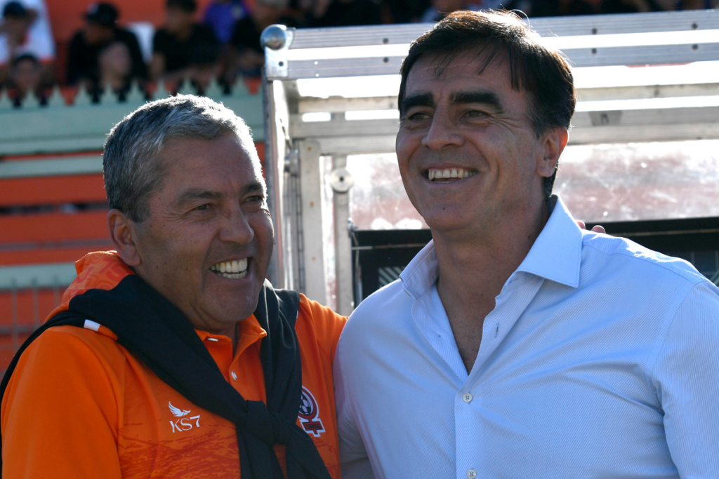 Gustavo Huerta y Gustavo Quinteros se abrazan y sonríen en pleno partido de Colo-Colo y Cobresal durante la temporada 2023.