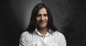 Primer plano al torso y rostro de Gabriel Mendoza con un fondo oscuro.