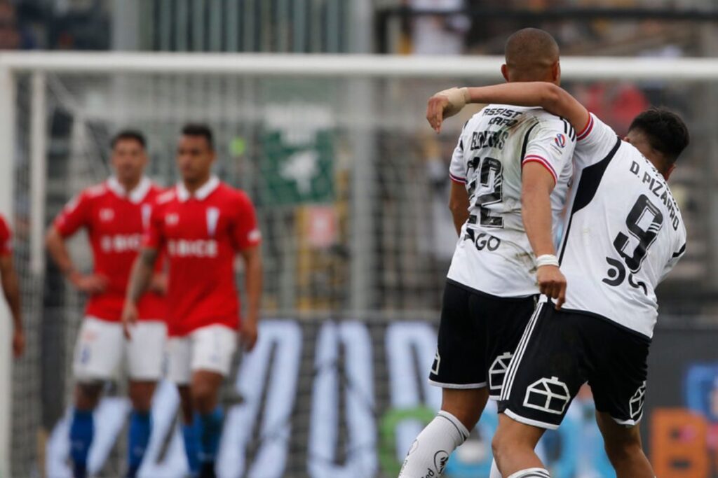 Jugadores de Colo-Colo abrazados y futbolistas de la UC en el fondo