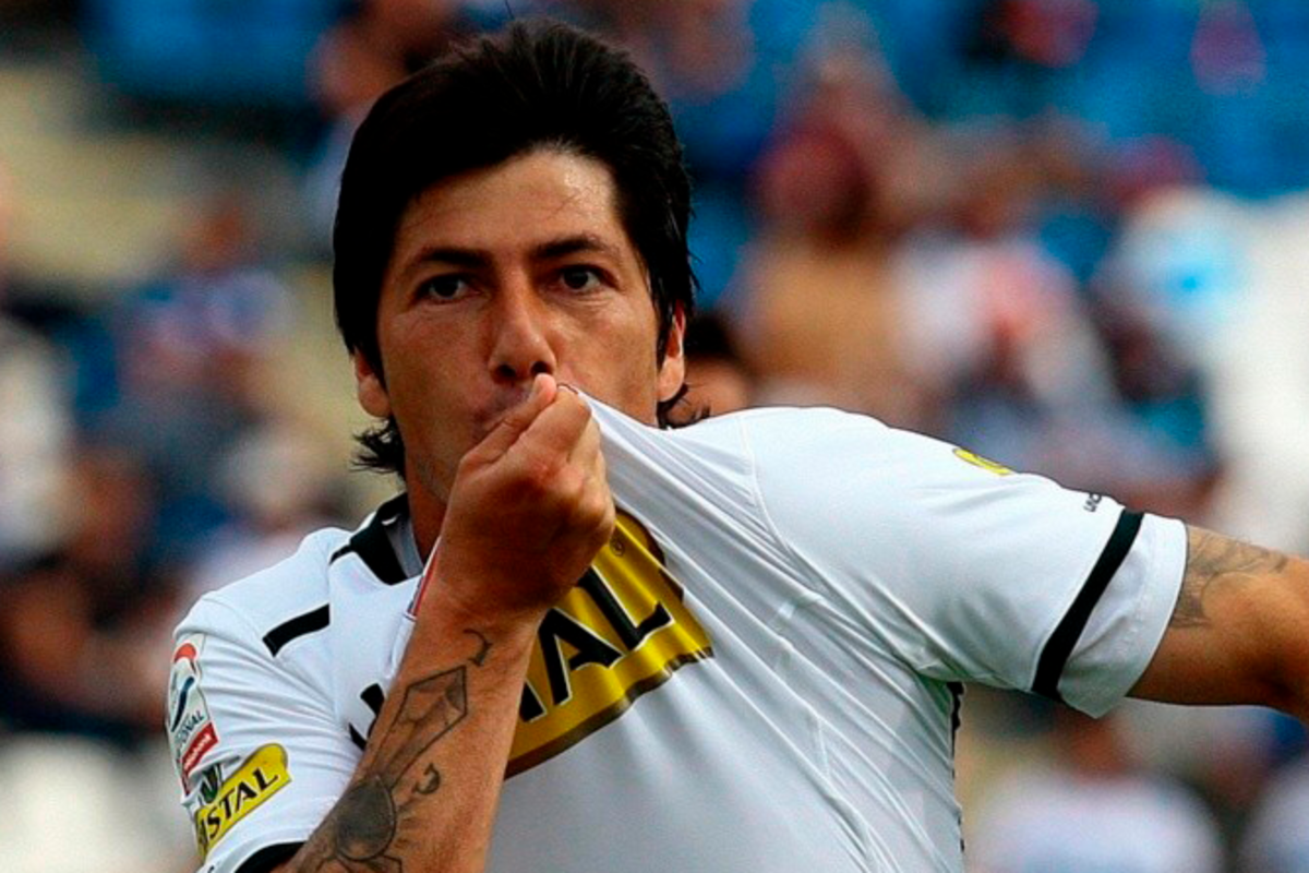 Jaime Valdés celebrando y besando el escudo de Colo-Colo tras anotar un gol.