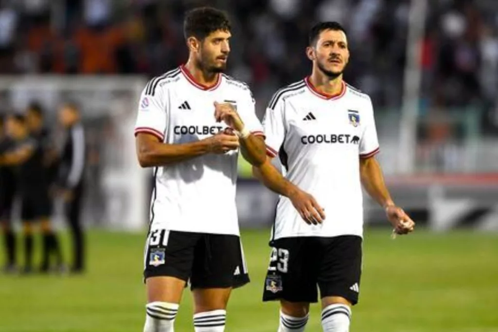 Dos jugadores de Colo-Colo con la camiseta blanca caminando