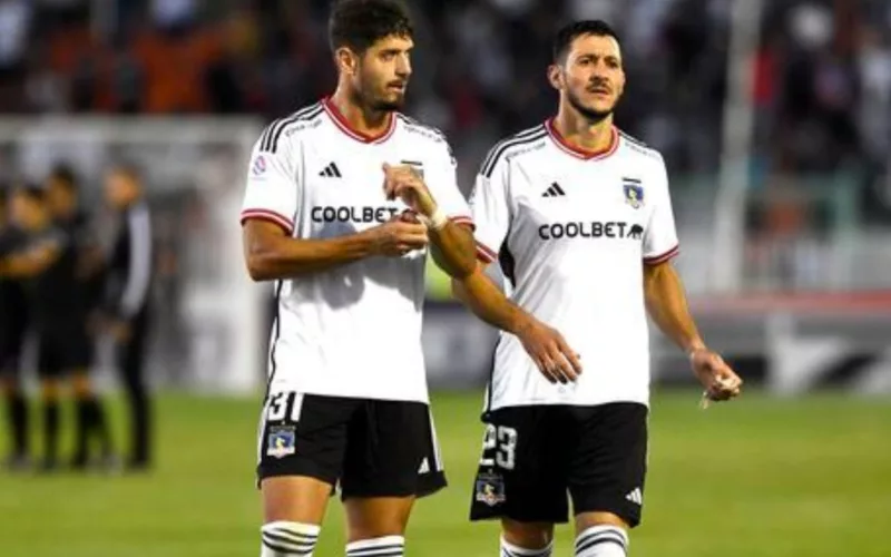 Dos jugadores de Colo-Colo con la camiseta blanca caminando