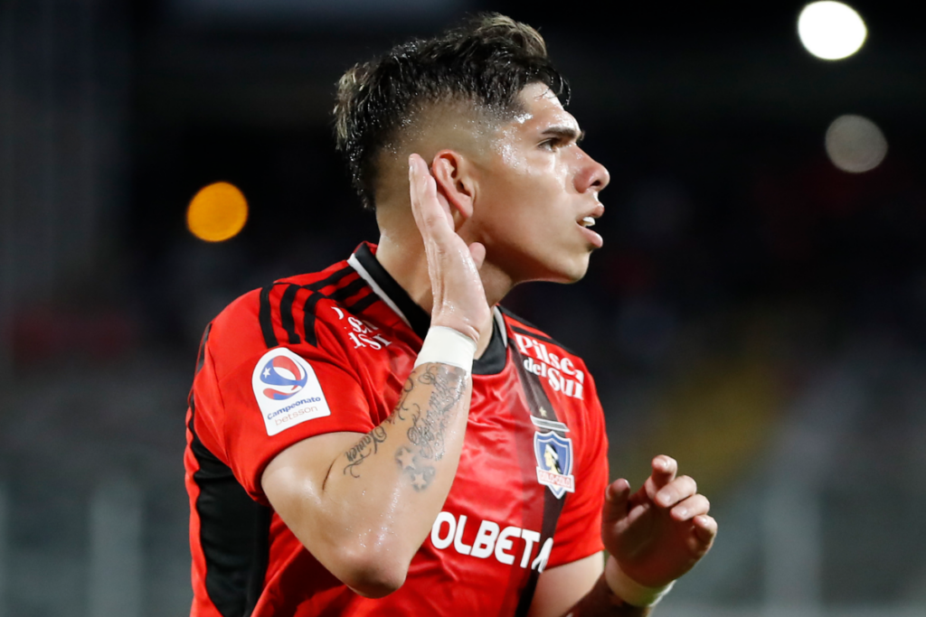 Carlos Palacios se toma la oreja con una mano en plena celebración de un gol con la camiseta de Colo-Colo durante la temporada 2023.