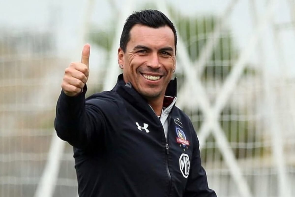 Primer plano a Esteban Paredes sonriendo, con un pulgar en alto mientras usa indumentaria de Colo-Colo.