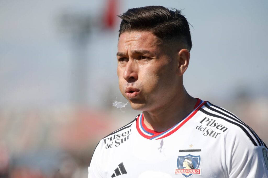 Primer plano al rostro de Óscar Opazo ,mientras tira agua desde su boca, mientras utiliza la camiseta de Colo-Colo.