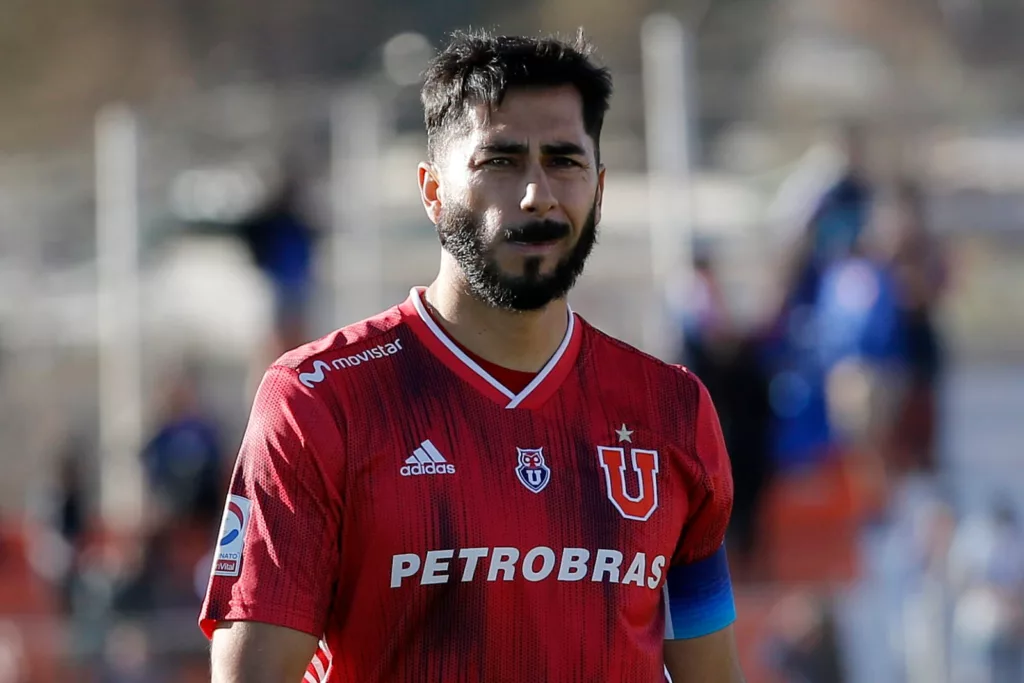 Primer plano a Johnny Herrera en un campo de juego con camiseta de Universidad de Chile y cara de preocupación.