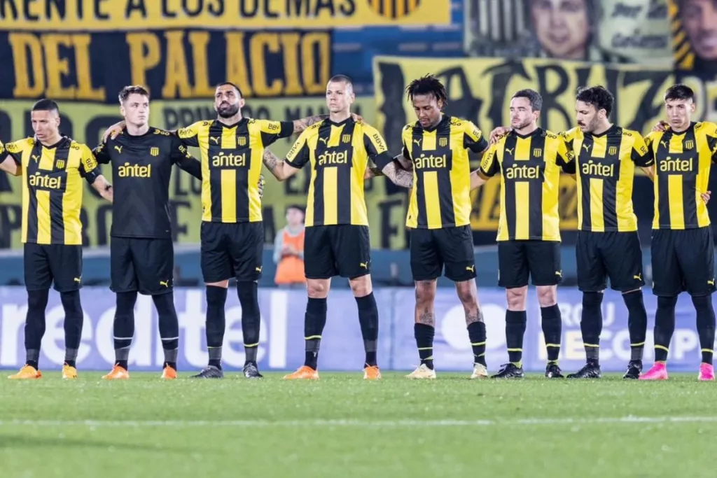 Jugadores de Peñarol abrazados en medio de la cancha