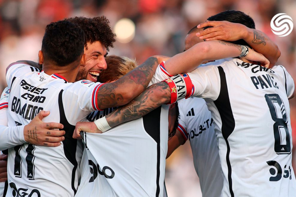 Futbolistas de Colo-Colo celebran abrazados un gol durante la temporada 2023.
