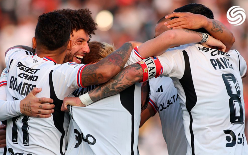 Futbolistas de Colo-Colo celebran abrazados un gol durante la temporada 2023.