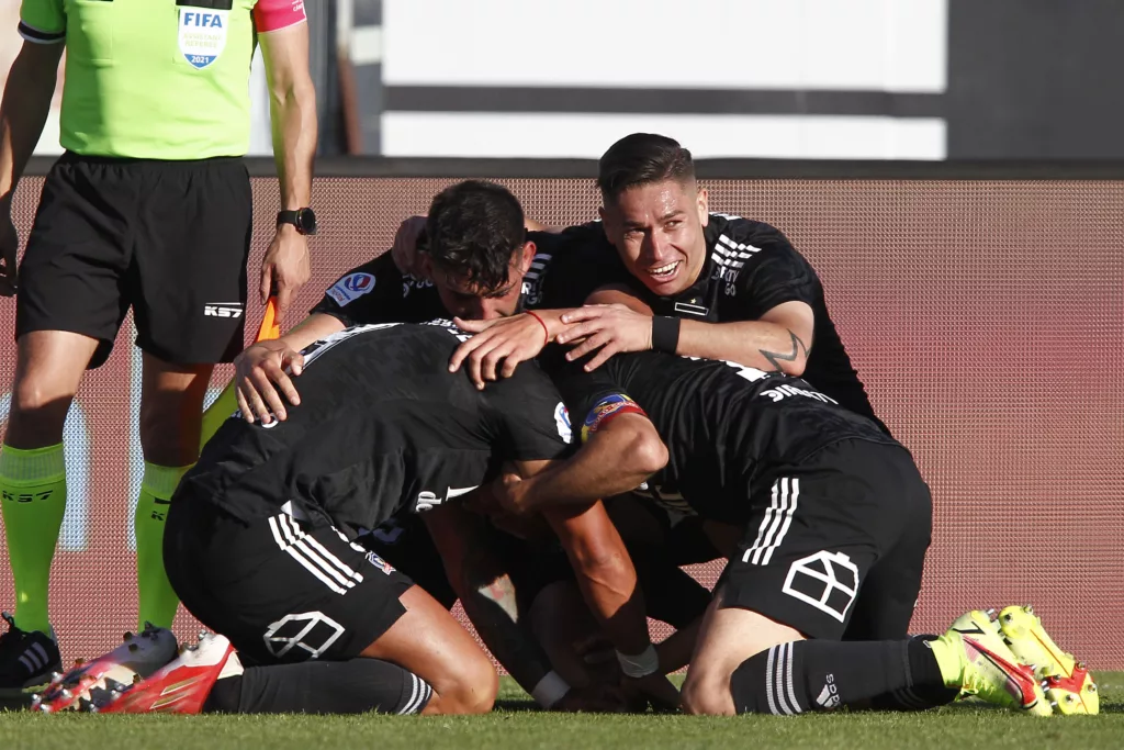 Futbolistas de Colo-Colo se abrazan y celebran un gol durante la temporada 2021 en el Estadio Monumental.