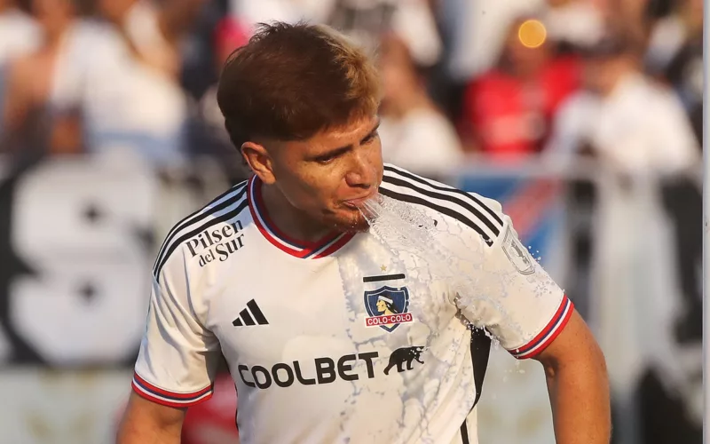 Leonardo Gil escupiendo un chorro de agua en pleno partido con la camiseta de Colo-Colo durante la temporada 2023.