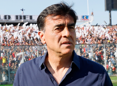 Primer plano al rostro de Gustavo Quinteros con la barra de Colo-Colo de fondo durante el segundo semestre de la temporada 2023.