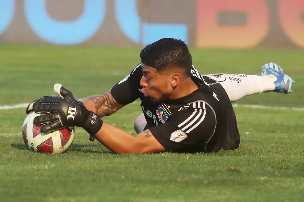 Brayan Cortés atajando un balón en pleno partido con la camiseta de Colo-Colo durante la temporada 2023.
