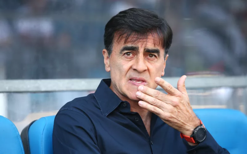 Gustavo Quinteros con la mano en la boca mientras dirigía un partido