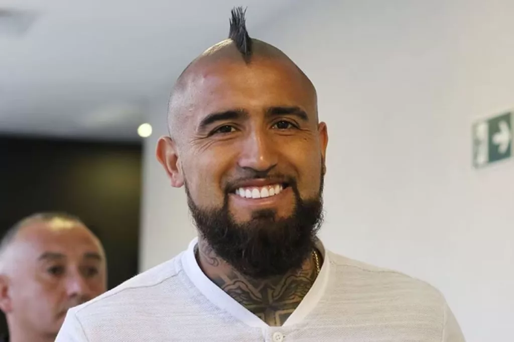 Primer plano de Arturo Vidal sonriendo mientras usa una polera blanca