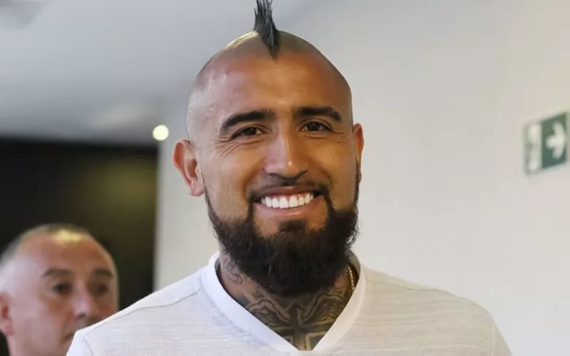 Primer plano de Arturo Vidal sonriendo mientras usa una polera blanca