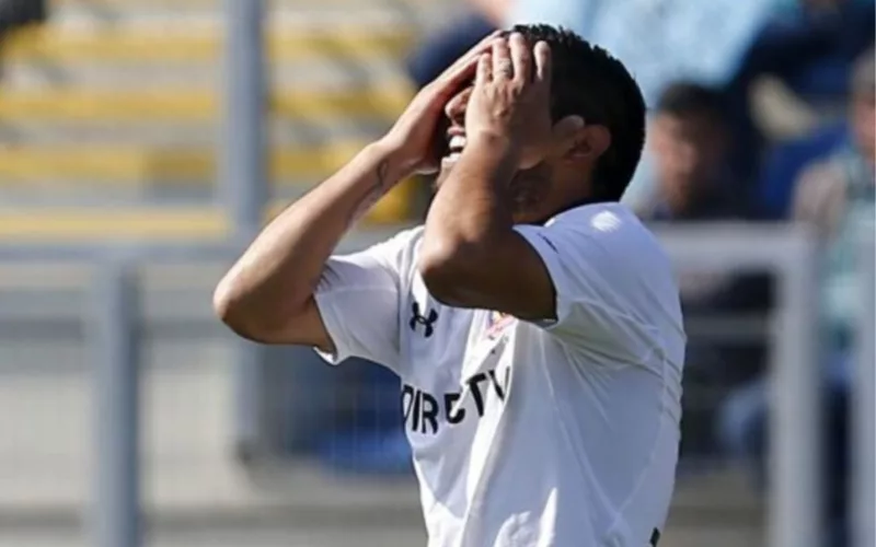 Futbolista de Colo-Colo con las manos en su rostro.
