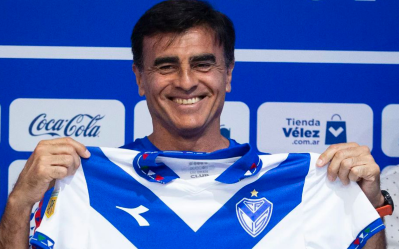 Gustavo Quinteros sostiene la camiseta de Vélez Sarsfield y sonríe ante las cámaras en su presentación oficial en el conjunto de Liniers de cara a la temporada 2024.
