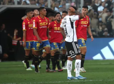 Marcos Bolados tomándose la cabeza mientras jugadores de Unión Española celebran un gol.