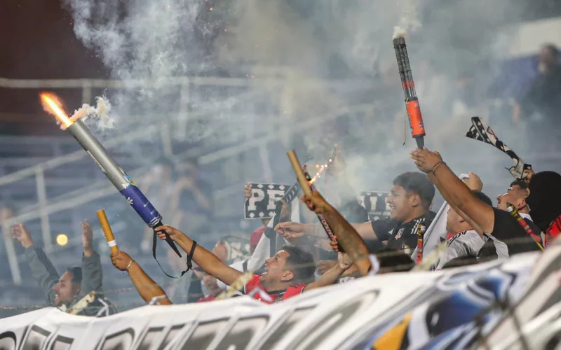 Hinchas de Colo-Colo lanzan fuegos artificiales en pleno encuentro ante Liverpool de Uruguay por el torneo Serie Río de La Plata 2024.