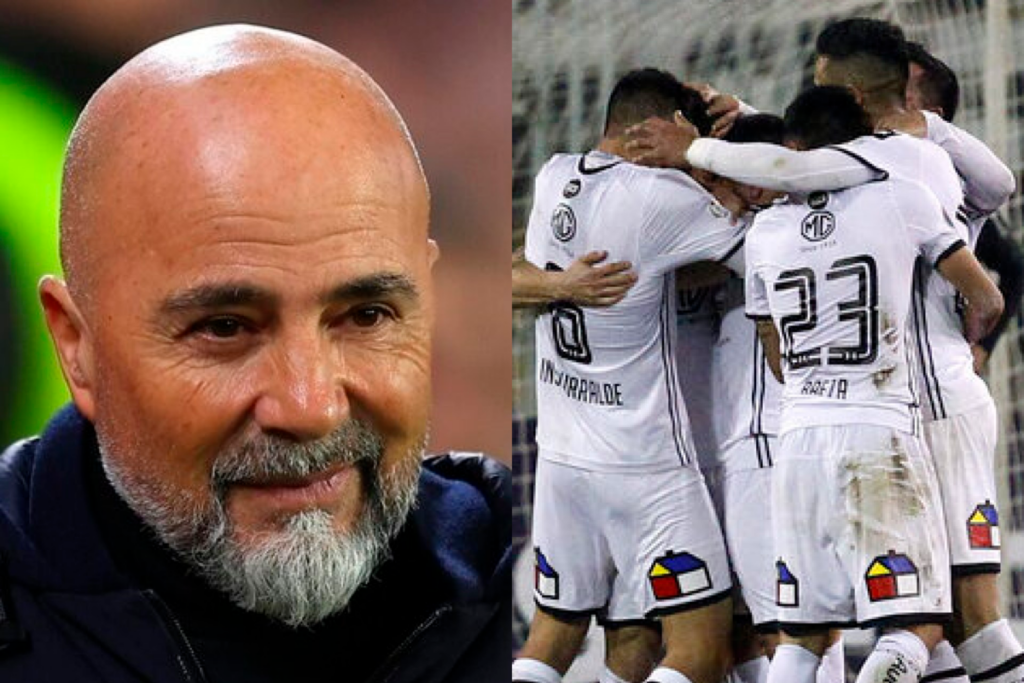 Primer plano al rostro sonriente del entrenador de fútbol profesional, Jorge Sampaoli, mientras que a mano derecha aparecen los jugadores de Colo-Colo celebrando un gol durante la temporada 2018.