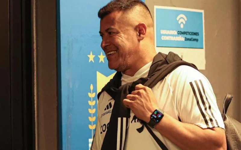 Jorge Almirón sonriendo mientras usa la camiseta blanca de Colo-Colo