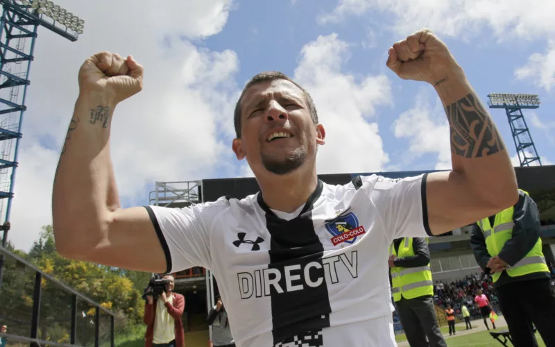 Emiliano Vecchio celebrando un gol con los brazos en alto con la camiseta de Colo-Colo.