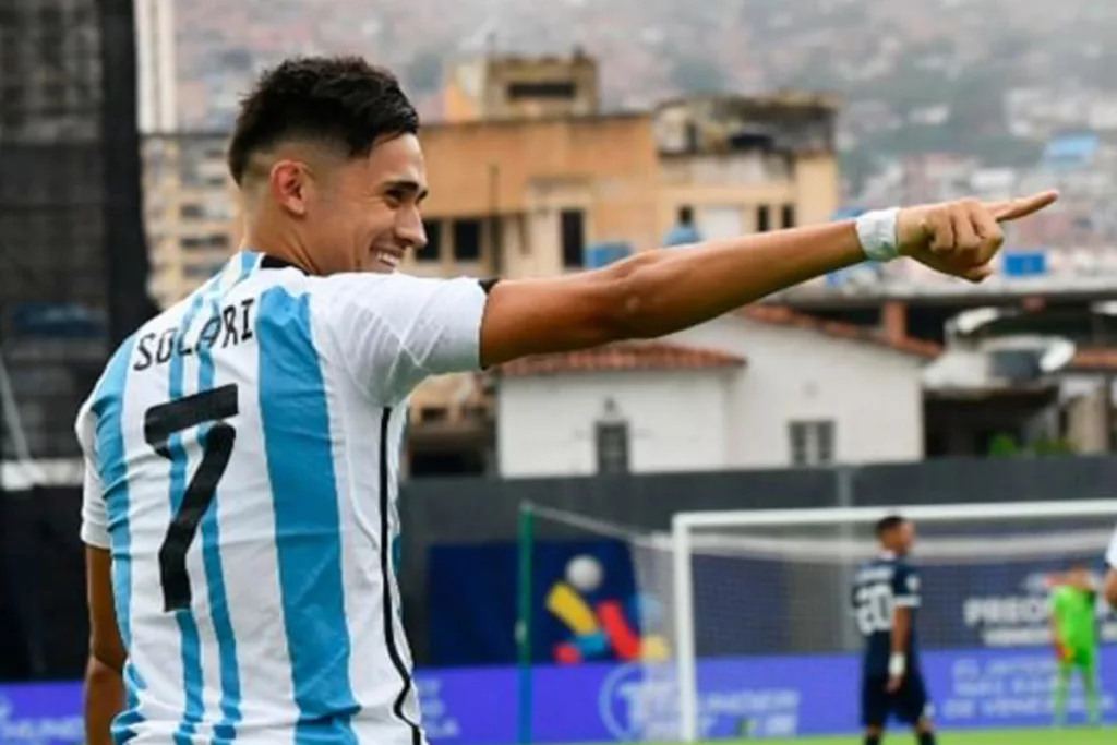 Pablo Solari celebrando un gol con la camiseta de la selección argentina y señala a alguien con su brazo derecho.
