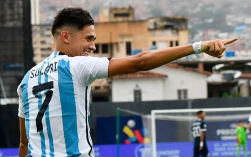 Pablo Solari celebrando un gol con la camiseta de la selección argentina y señala a alguien con su brazo derecho.