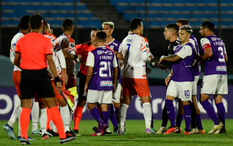 Futbolistas de Puerto Cabello y Defensor Sporting se enfrentan en una discusión junto al cuerpo arbitral durante la Copa Libertadores 2024.