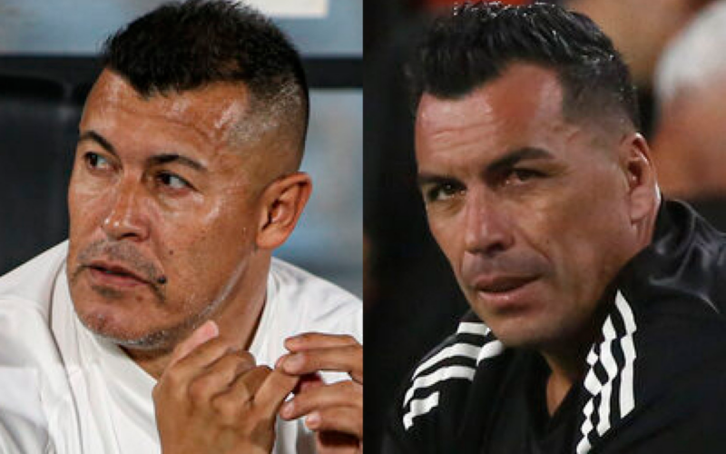 Primer plano a los rostros pensativos de Jorge Almirón y Esteban Paredes, entrenador de Colo-Colo durante la temporada 2024 y ex futbolista profesional, respectivamente.