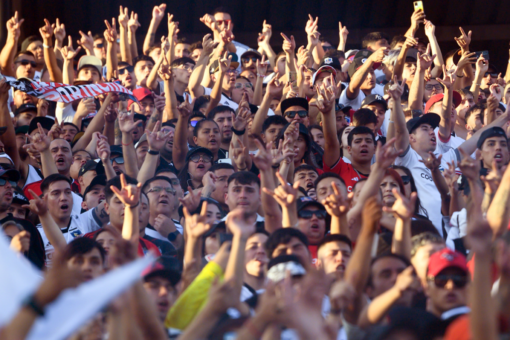Hinchas de Colo-Colo alzan sus manos y alientan al equipo en las tribunas del Estadio Monumental.