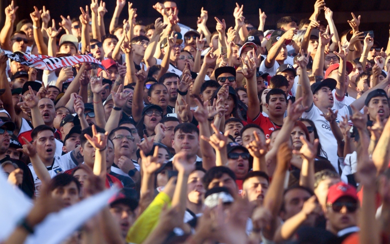 Hinchas de Colo-Colo alzan sus manos y alientan al equipo en las tribunas del Estadio Monumental.