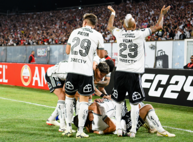 Jugadores de Colo-Colo se abrazan en el suelo y otros levantan sus brazos para alentar al público del Estadio Monumental en pleno partido por Copa Libertadores ante Sportivo Trinidense este 2024.